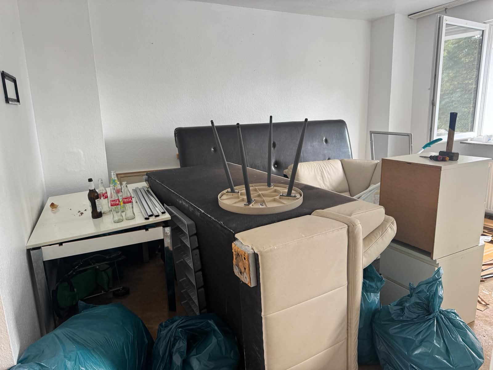 Wohnungsentrümpelung vorher – Couch, Tisch, Müllsäcke und Hausrat in einem Wohnzimmer