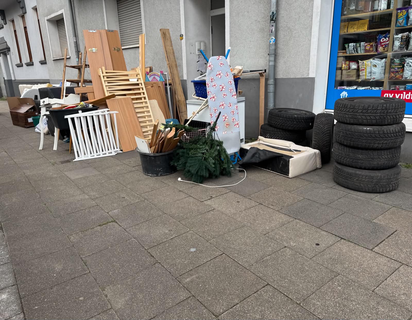 Haushaltsauflösung vorher – Sperrmüll, Reifen, Möbel und Hausrat stapeln sich auf dem Gehweg